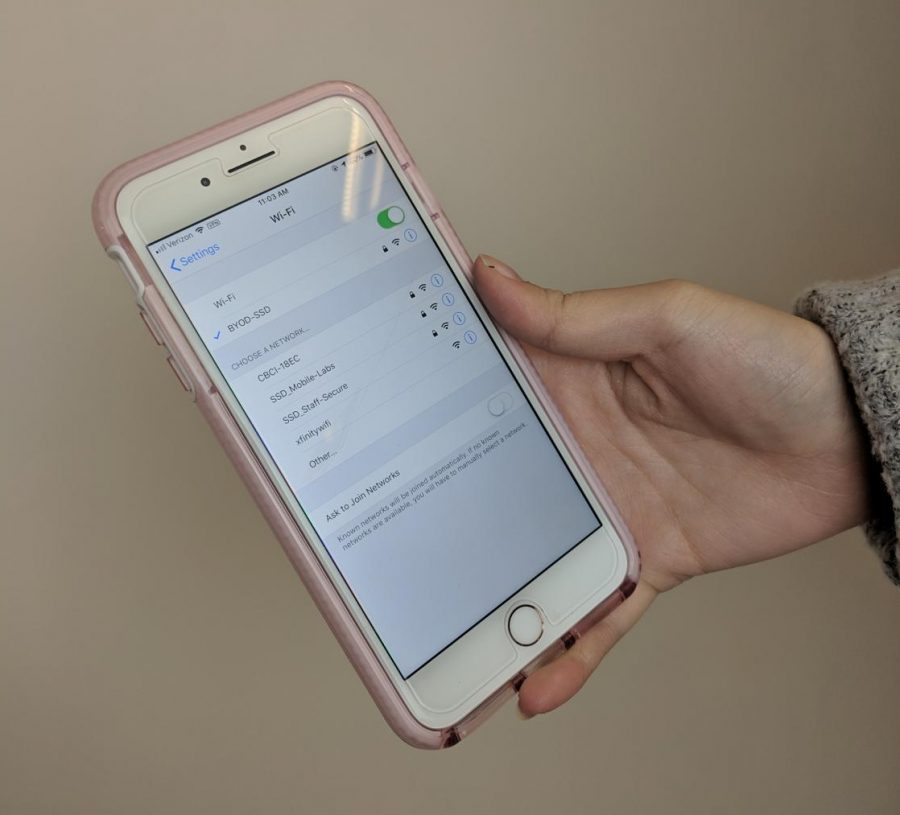 A student holding a phone while looking at the wifi.